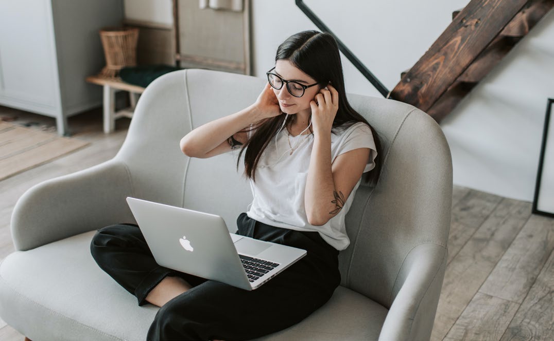 A person sitting alone on a chair with a laptop in their lap